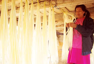 A weaver hangs straw under her house to dry.