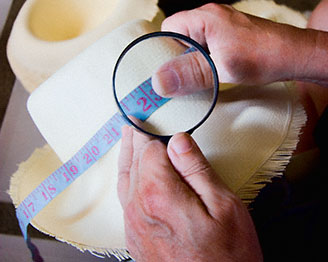 B Brent Black examining hat under a magnifying glass.